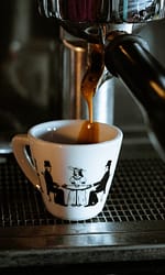 white and black ceramic mug on black and silver coffee maker