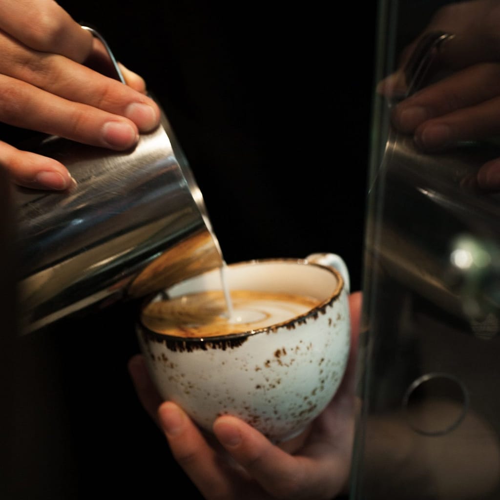 person holding clear glass cup with white liquid