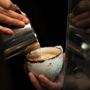 person holding clear glass cup with white liquid