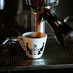 white and black ceramic mug on black and silver coffee maker