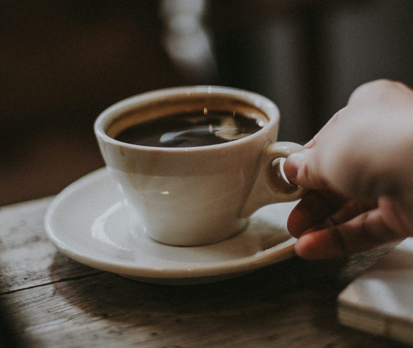 person holding white ceramic cup with liquid